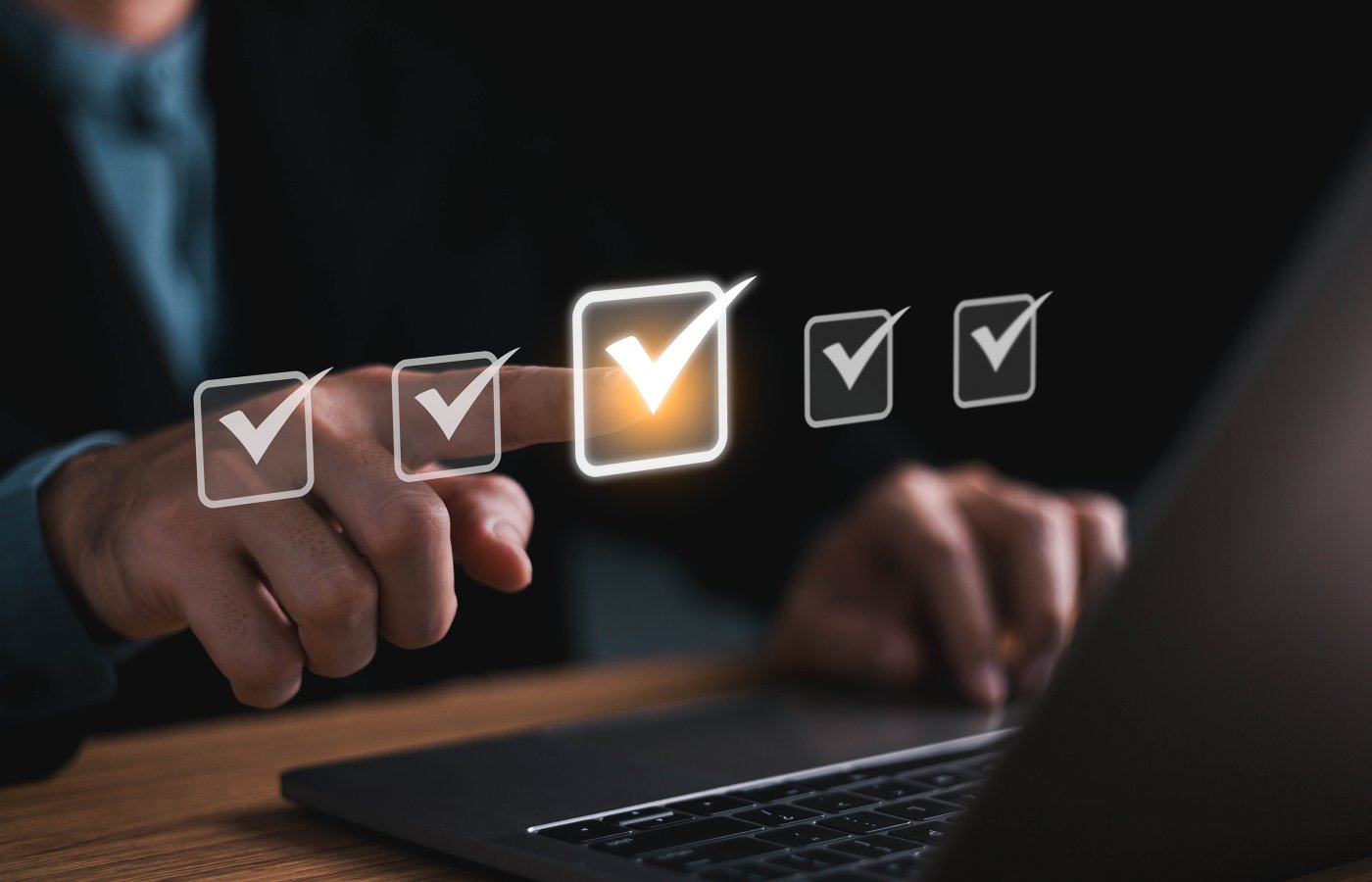close up of a person at a computer and pointing to a row of abstract checkmarks in the air 