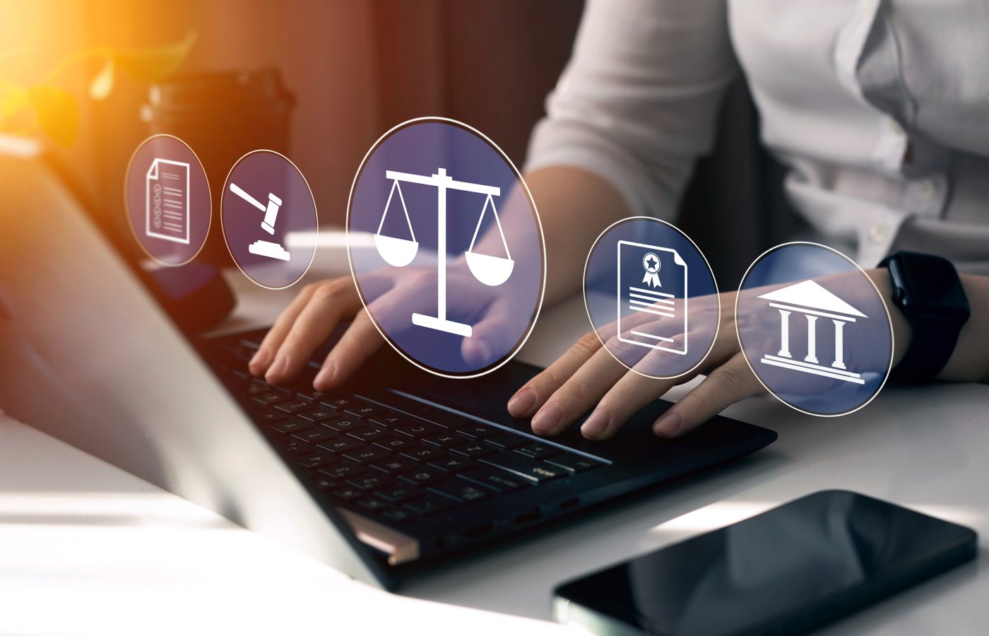 closeup of hands on a laptop keyboard with images of law-related icons floating above.