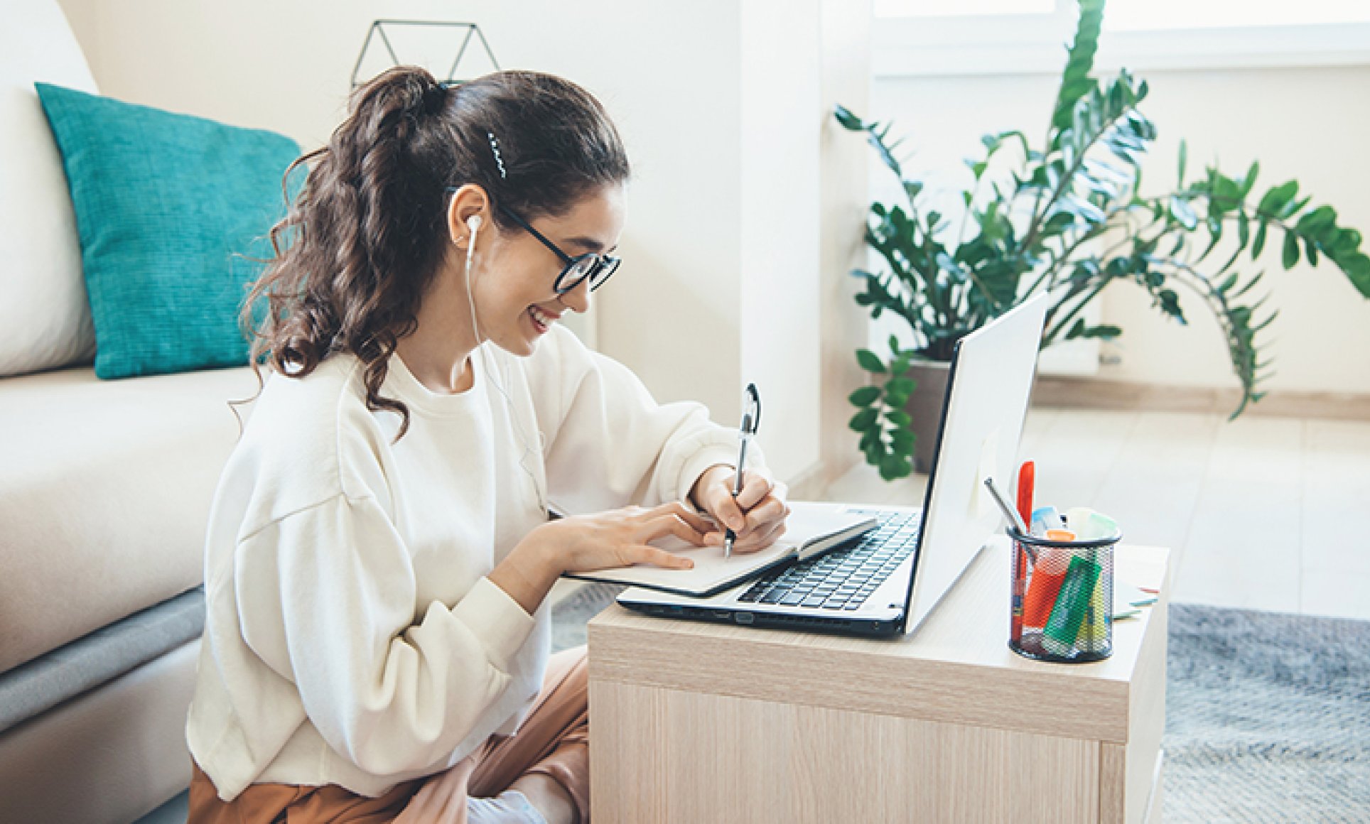 Woman sitting on floor writing with open laptop