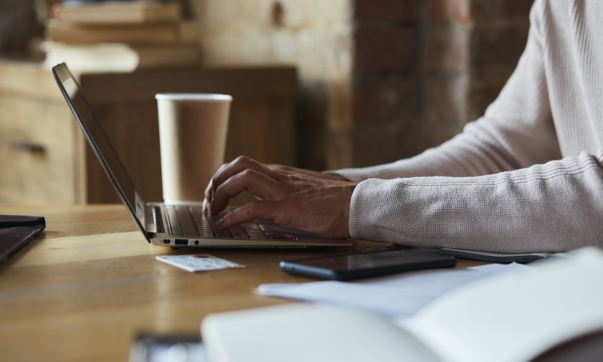person typing on keyboard with coffee in background