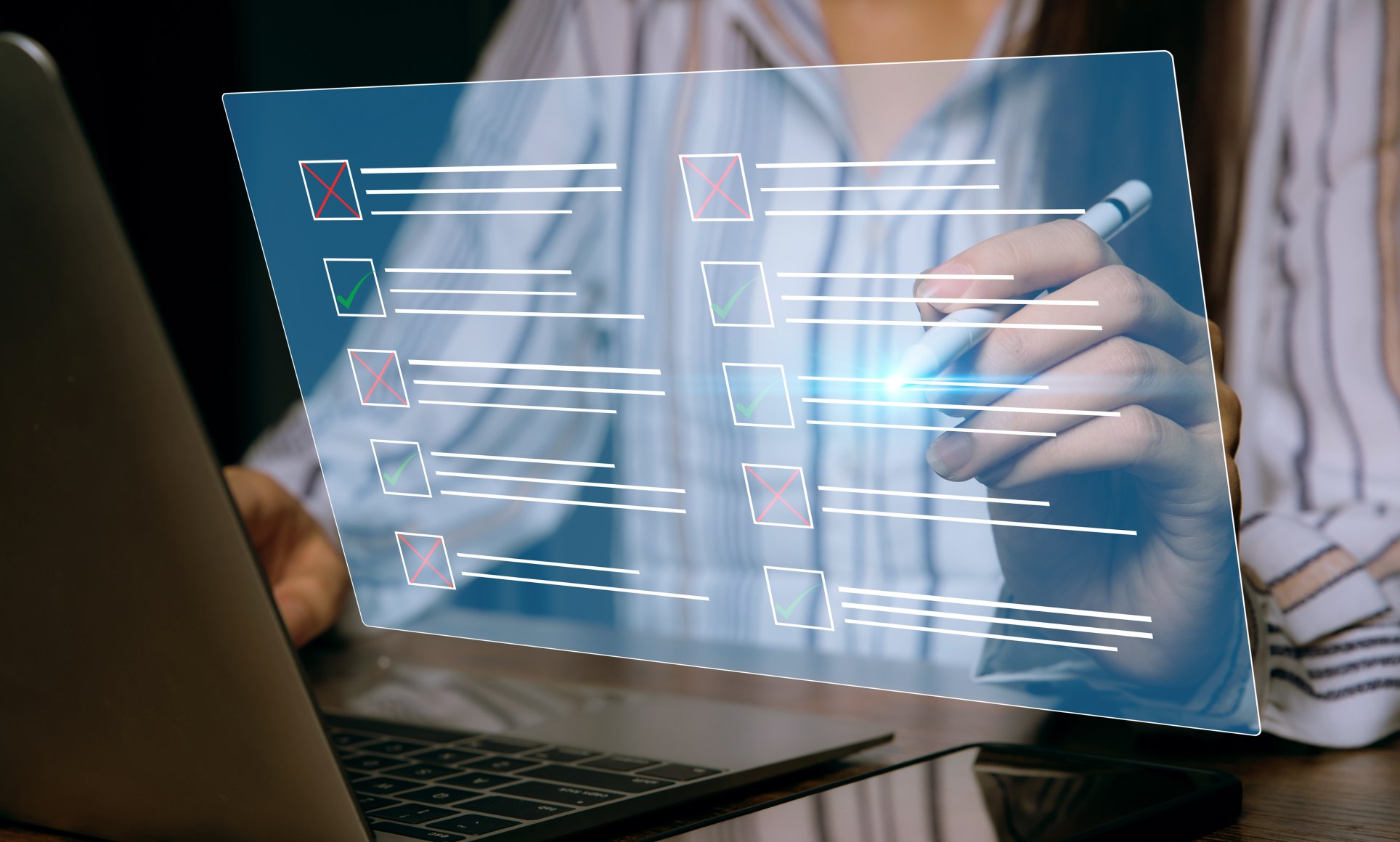 close up of a person selecting a check box next to text in a floating transparent screen above a computer. Portrays testing concept. 