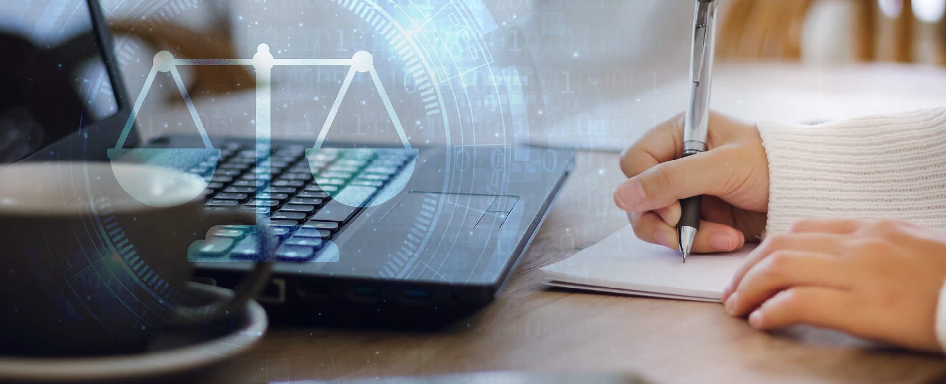 Close up of a person's hands writing on paper, with a laptop, cup of coffee, and phone also on the table. There is legal scale icon that overlays the image as well.