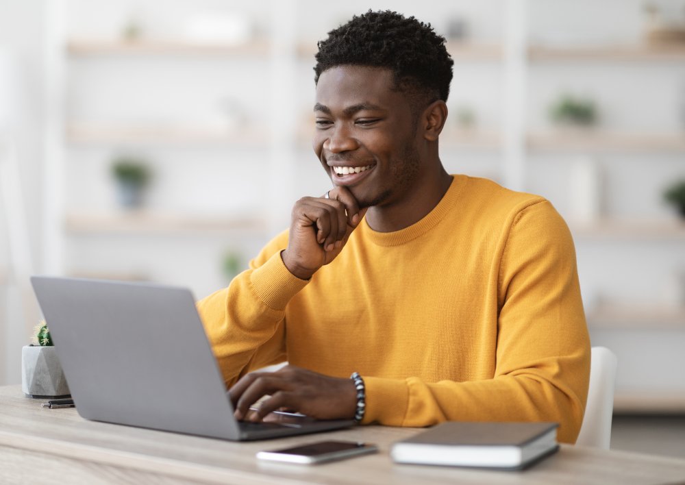 Adult looking at a laptop screen and smiling. 