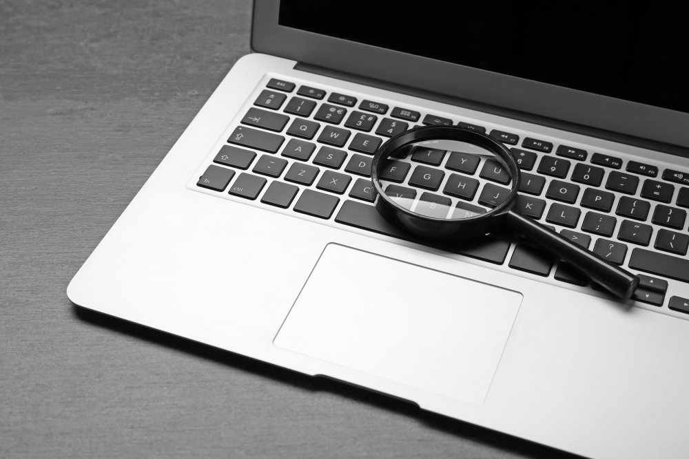 Closeup of a laptop keyboard with a magnifying glass resting on it