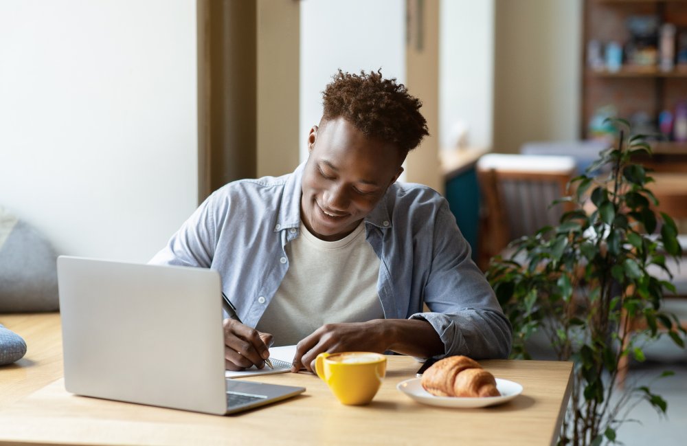 adult male working at a computer in a relaxed environment with a cup of coffee