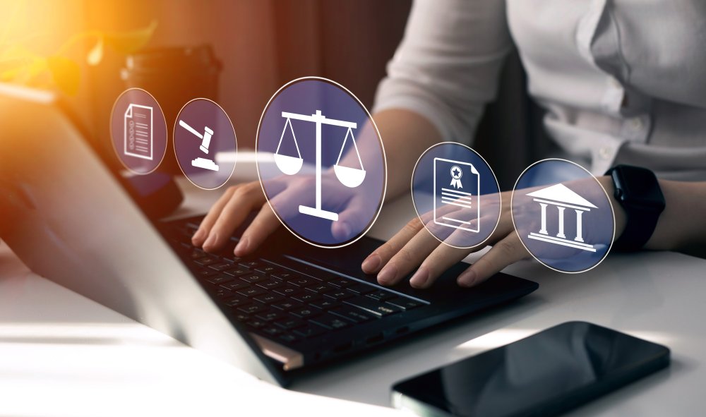 closeup of hands on a laptop keyboard with images of law-related icons floating above.